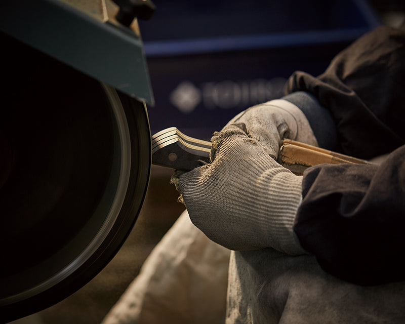Man working on kitchen knife handles in a workshop like environment. 