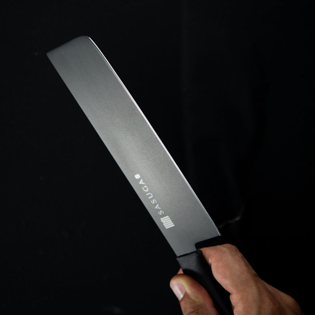 Knife with 'SASUGA' branding held against a black background