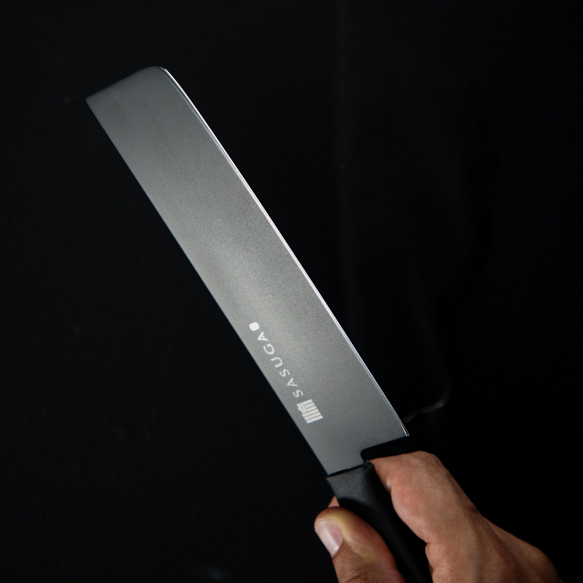 Knife with 'SASUGA' branding held against a black background