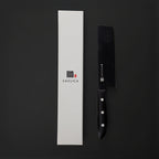 Black kitchen knife with black handle and white blade on a black background, next to a white box with 'SASUGA' branding.