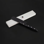 Black ceramic knife with a black sheath on a white box against a dark background