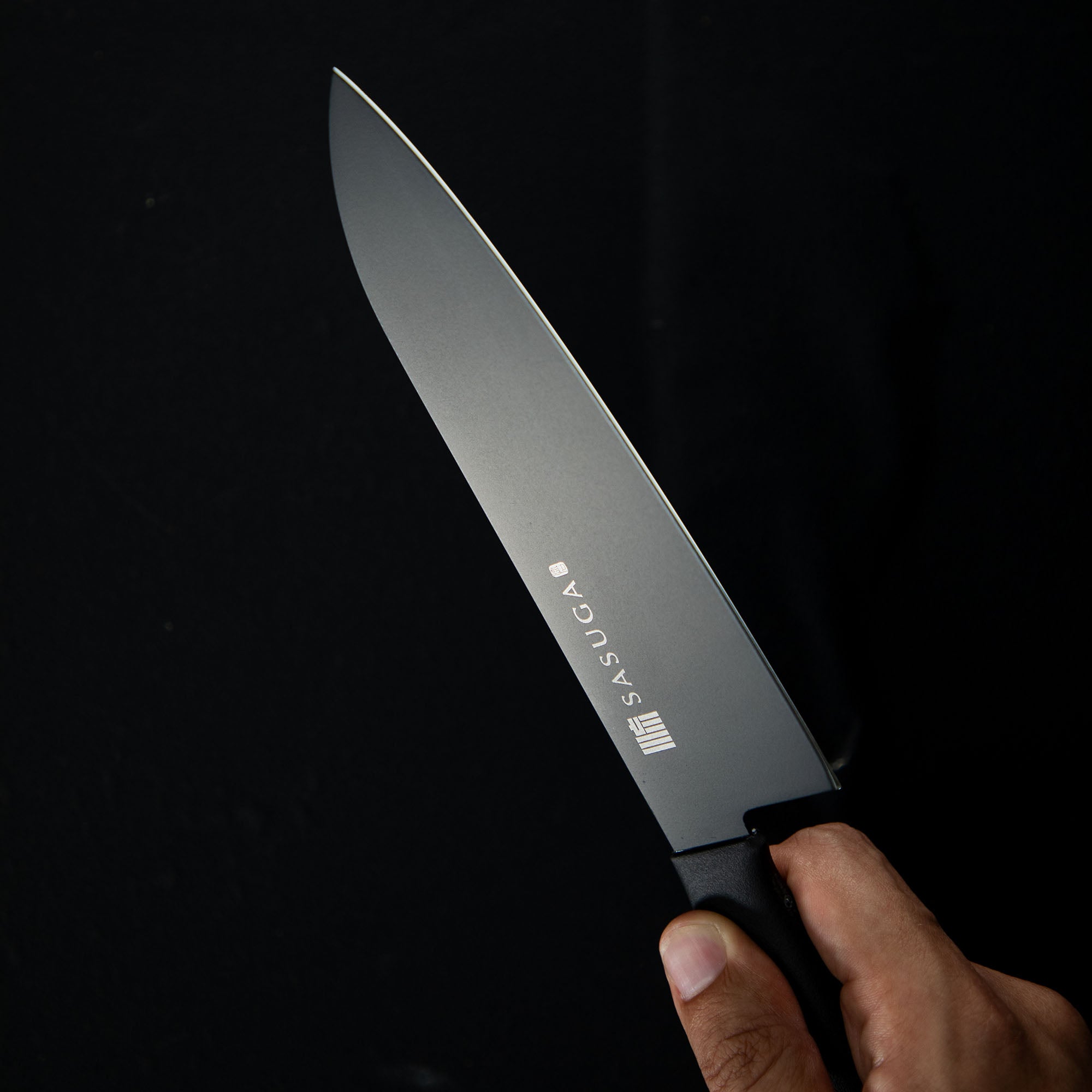 Knife with 'SASUGA' branding held by a hand against a black background